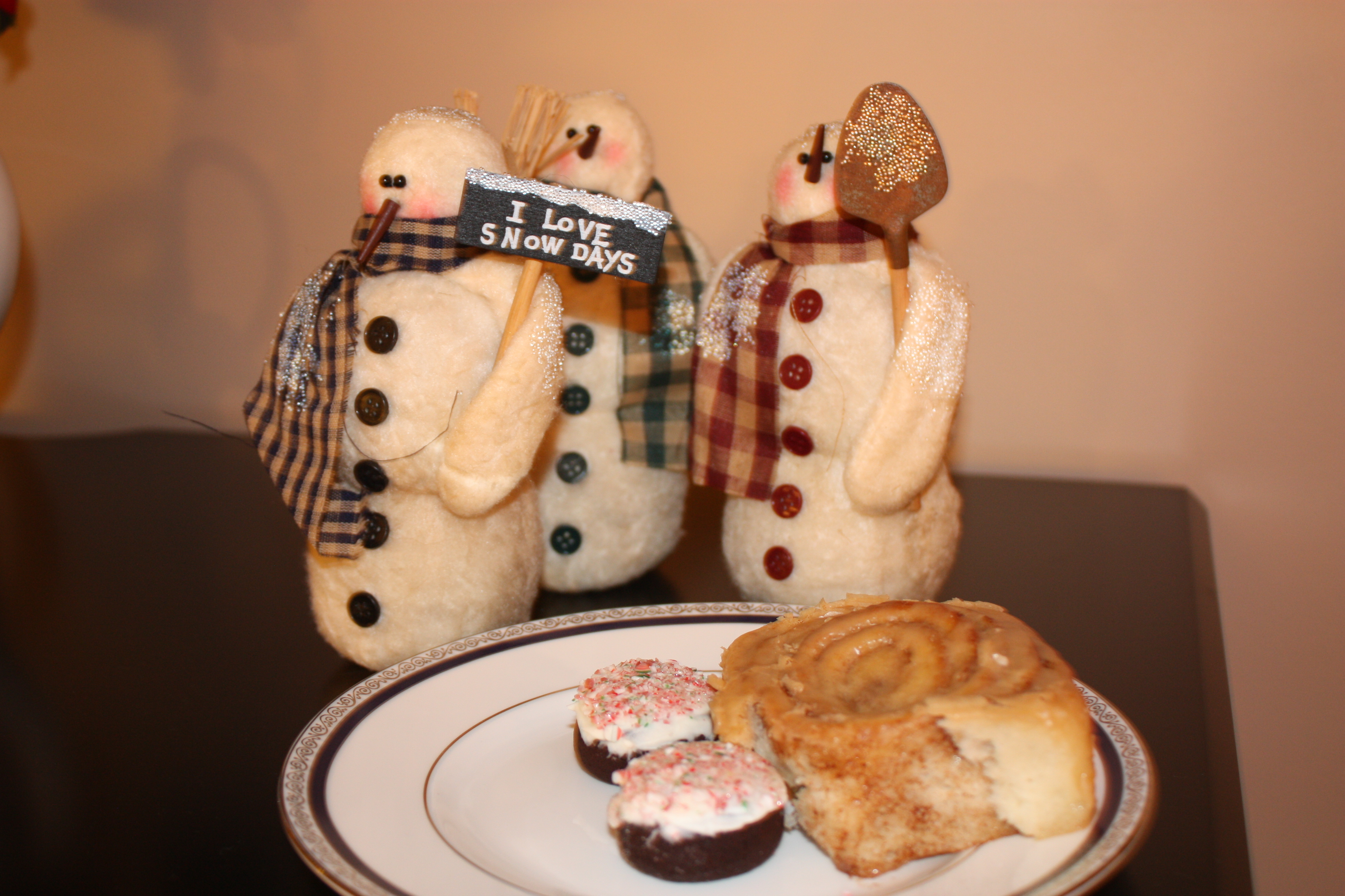 cinnamon scroll on plate with brownies and snowmen in background cinnamon scroll on plate with brownies and snowmen in background