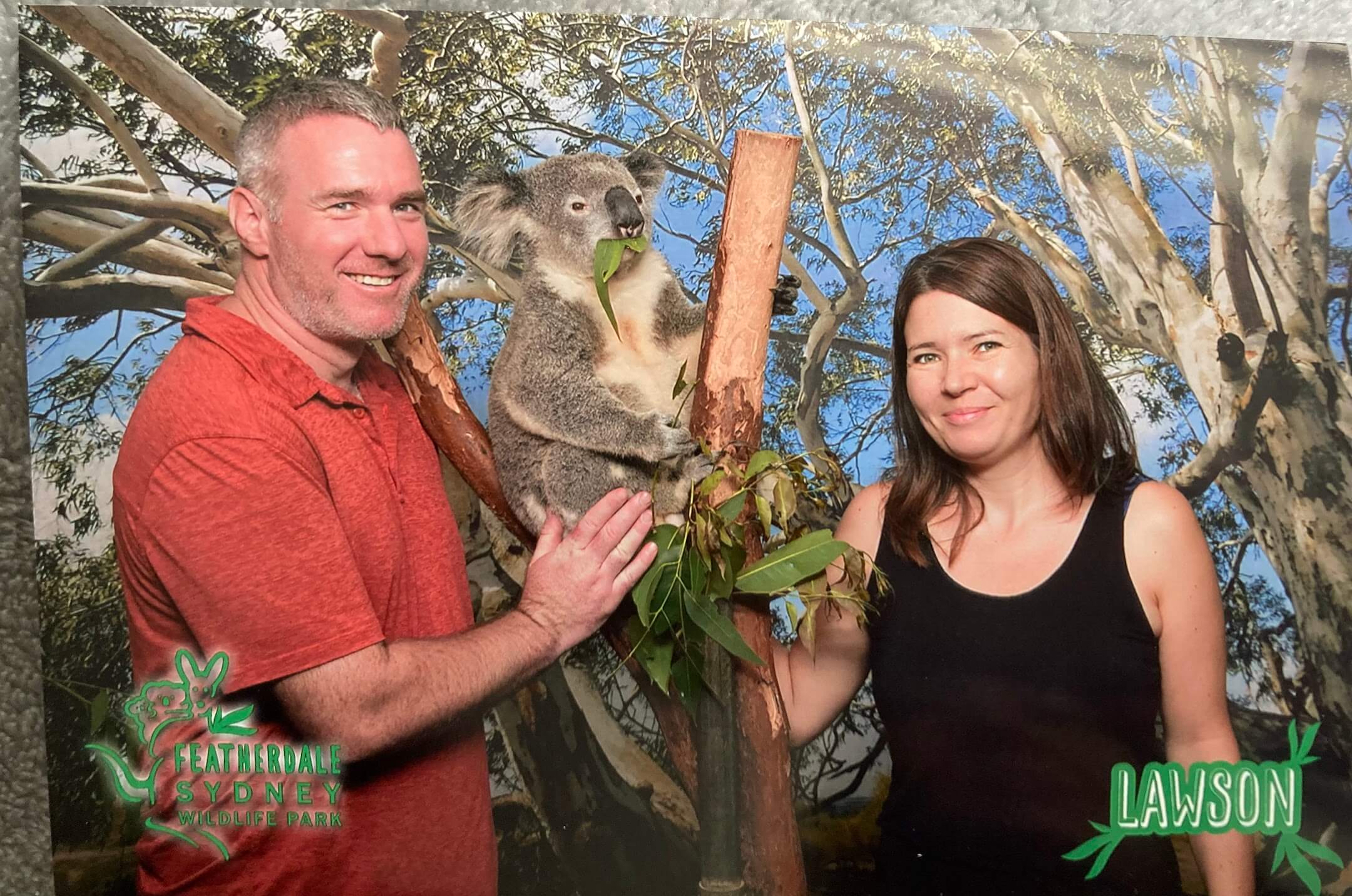 a man and a woman pose for a photo with a koala