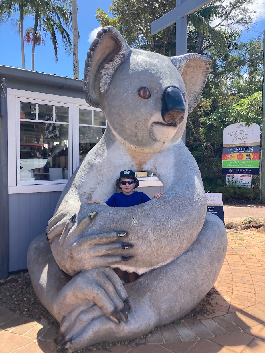 Boy standing inside a large koala statue