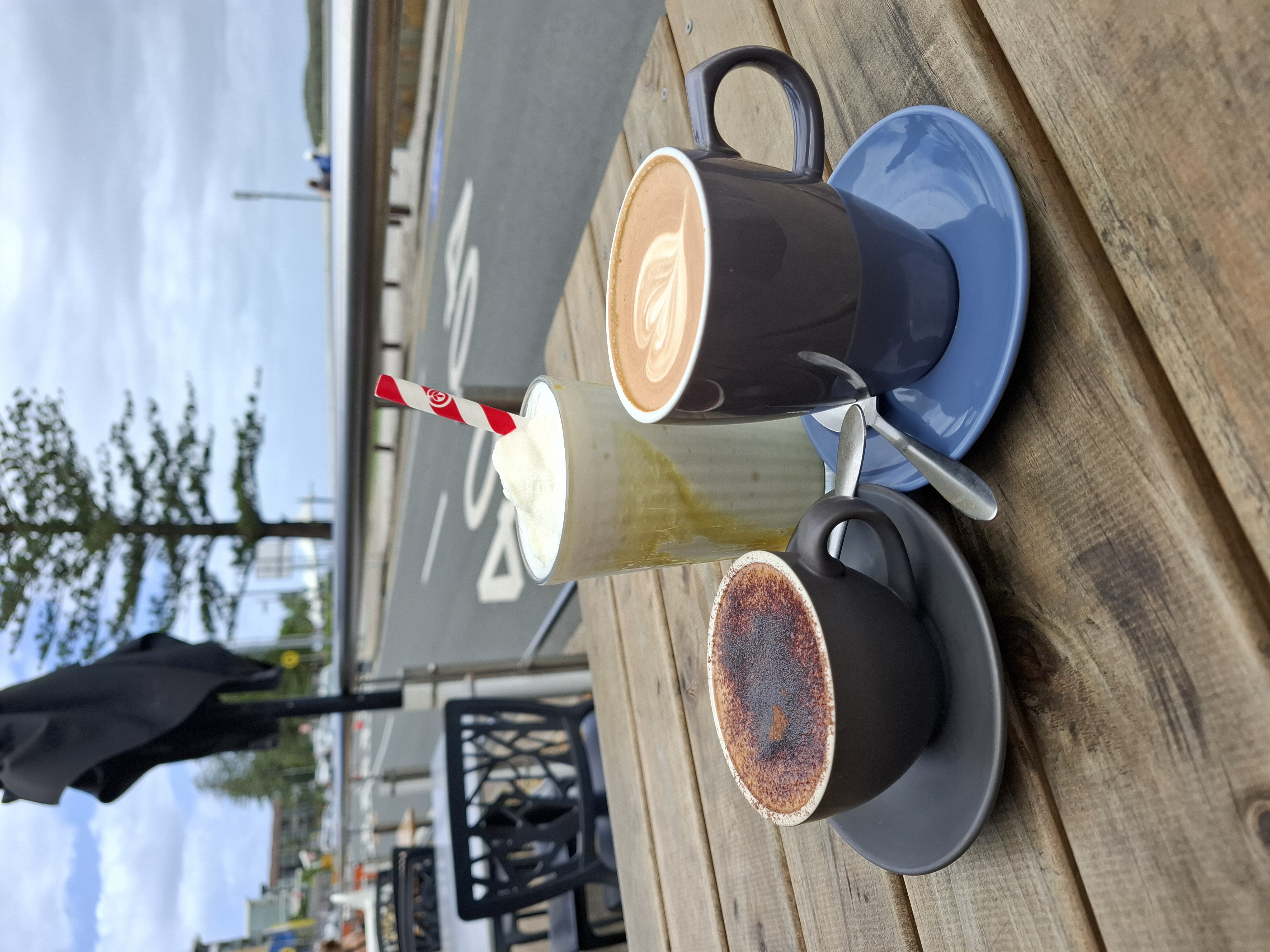 3 coffees on a table by the beach beside a roadway 3 coffees on a table by the beach beside a roadway