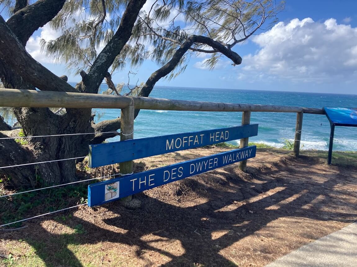 blue sign with white text that reads Moffat Beach The Des Dwyer Walkway