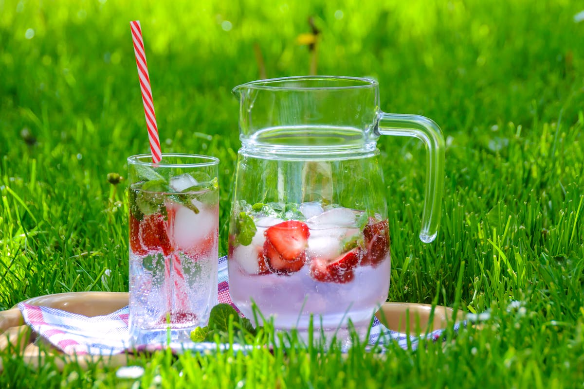 pitcher of strawberry water sitting on grass pitcher of strawberry water sitting on grass