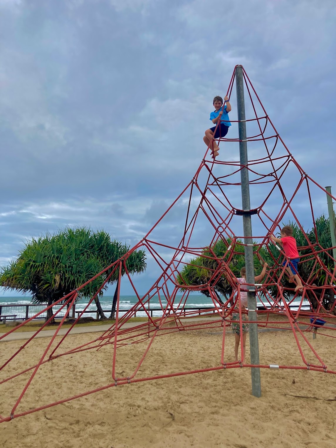kids on climbing play structure with ocean in background kids on climbing play structure with ocean in background
