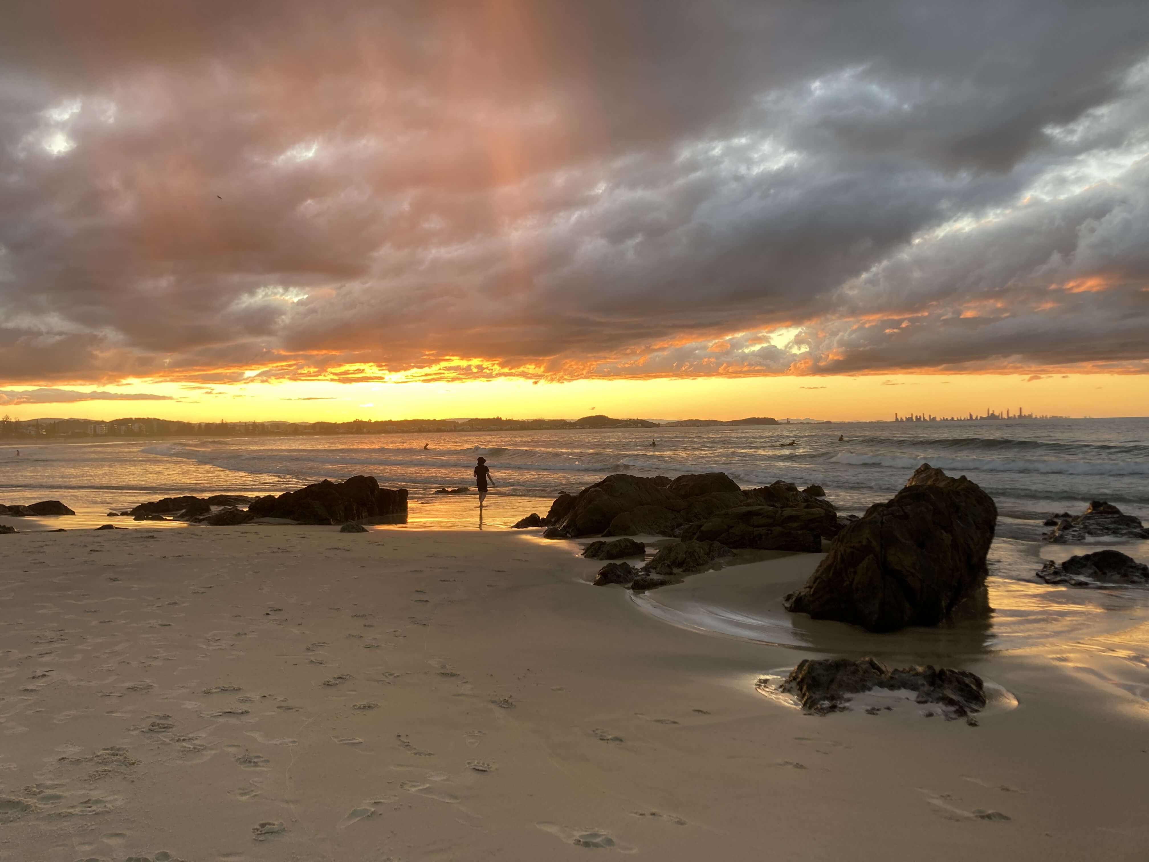 golden beach and golden sunset as surfers in distance enjoy last rays of daylight golden beach and golden sunset as surfers in distance enjoy last rays of daylight